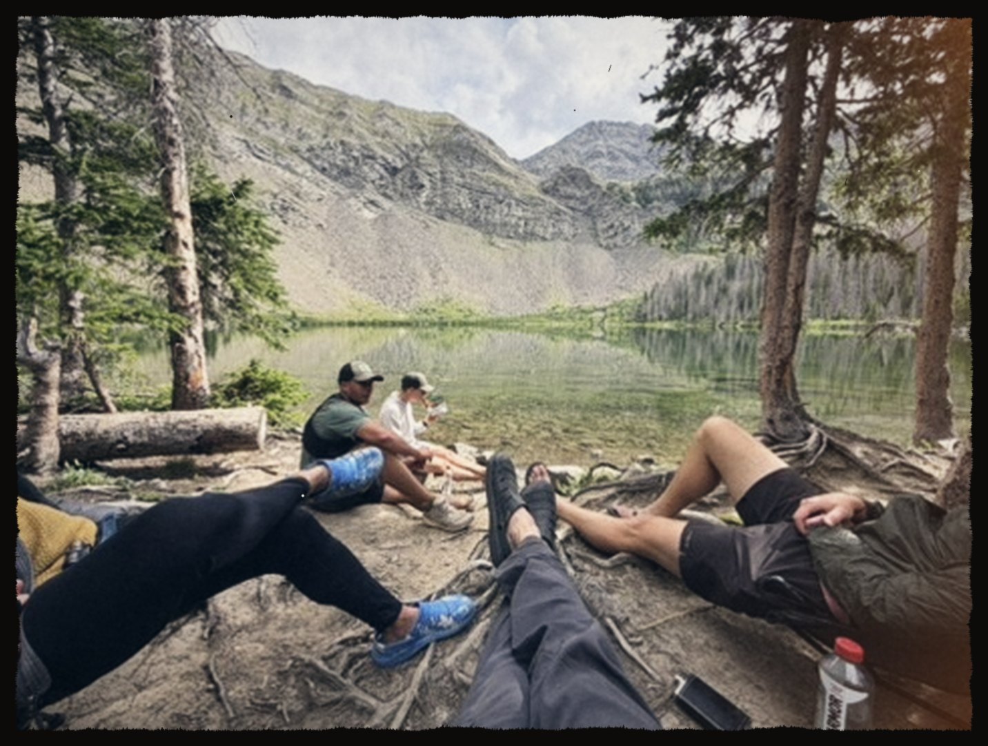 Hikers resting by an alpine lake below a ridge