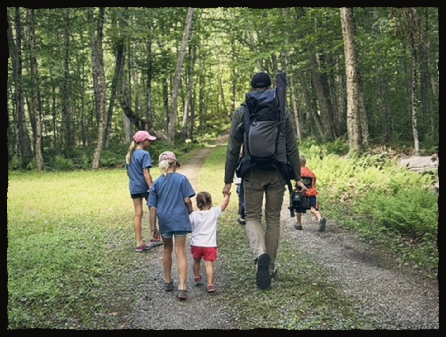 Walking a forest path with kids, camera bag on back